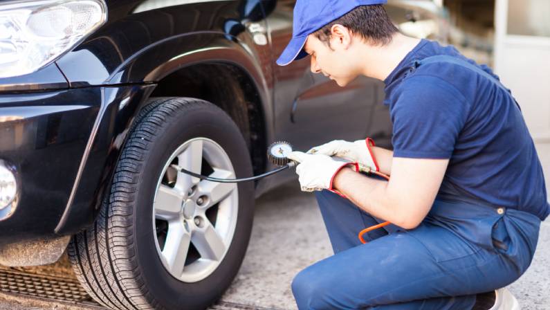 man filling air in the tires of his car