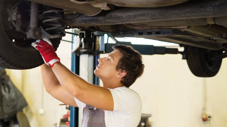 Serviceman checking suspension in a car workshop