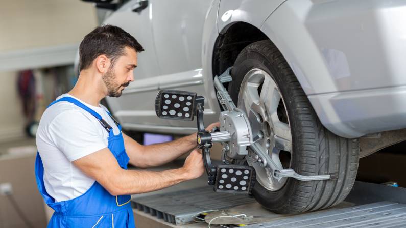 car mechanic installing sensor adjustment and automobile wheel
