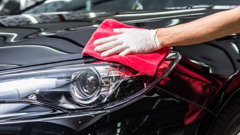 Car detailing series : Worker cleaning black car