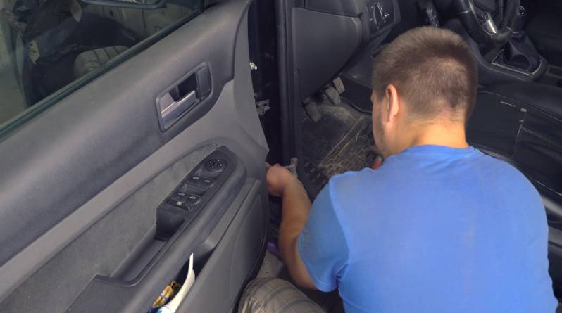 A man removes the door in the car.