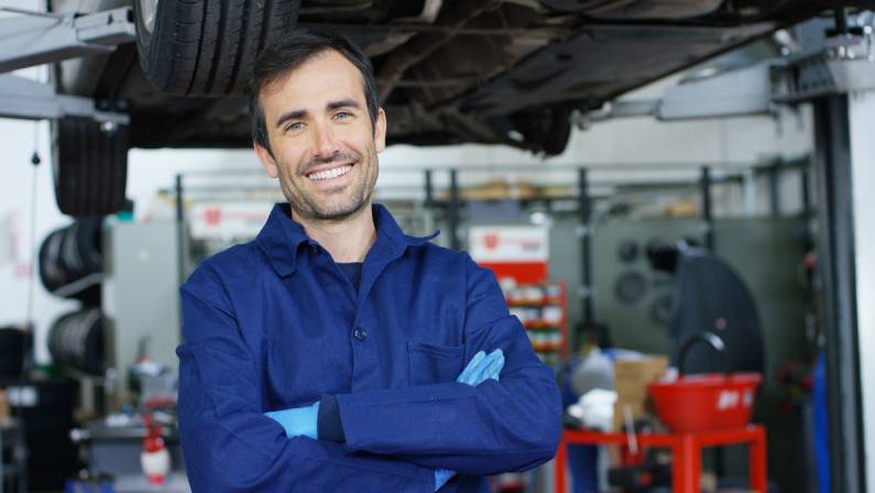 Portrait of a young beautiful car mechanic in a car workshop