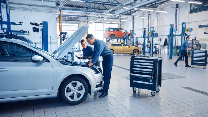 Two Mechanics in a Service are Inspecting a Car After They Got the Diagnostics Results.