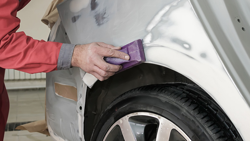 Car painter prepares the rear wing of the car for painting.