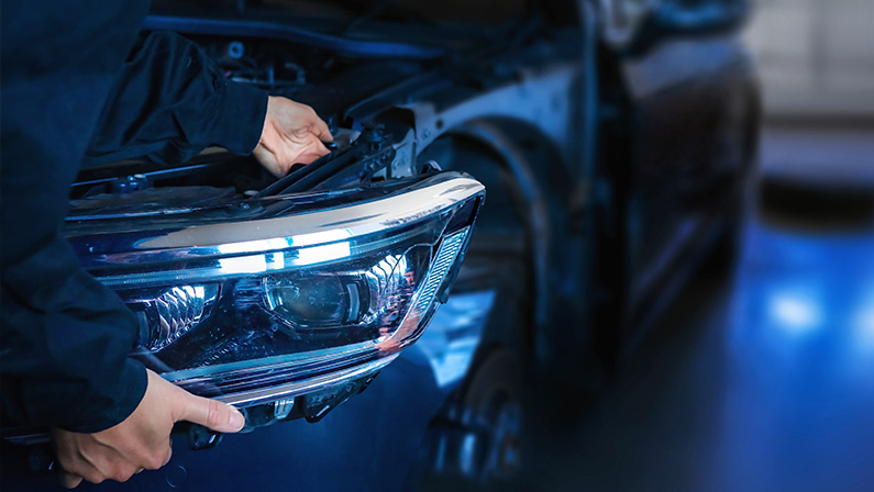 Mechanic changing car headlight in a workshop