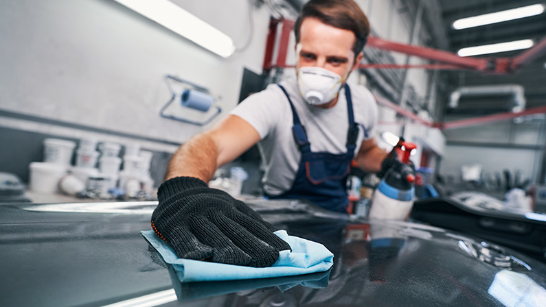 Hard-working male cleaning car in Houston auto body shop