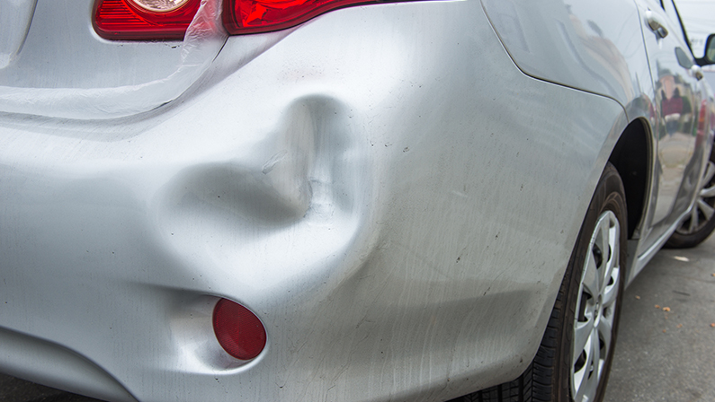 A car has a dented rear bumper after an accident