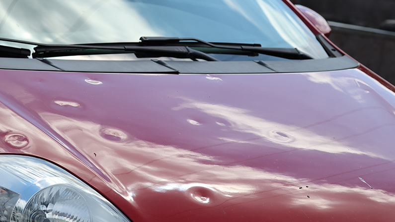 Hail damage at car, red colored car