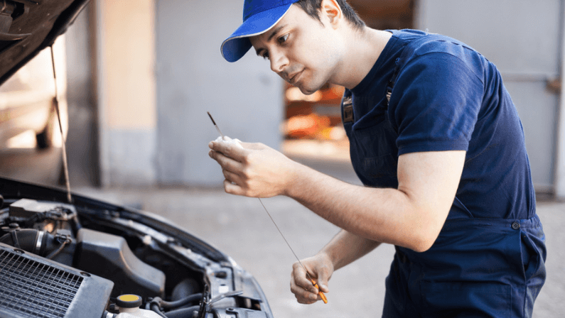 Mechanic checking the oil level in a car engine
