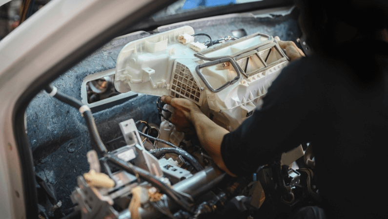 Auto mechanic installing air conditioning evaporator housing on the firewall ,car air conditioning repair and service.