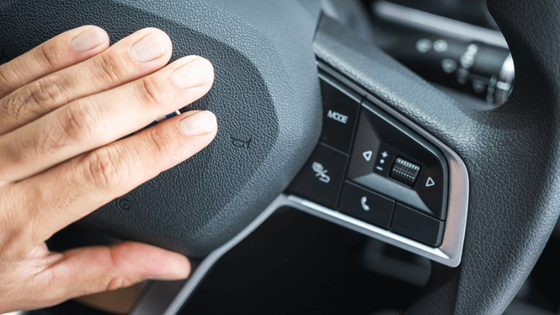 A car driver is using hand to bumping on the steering wheel to beeping the horn.