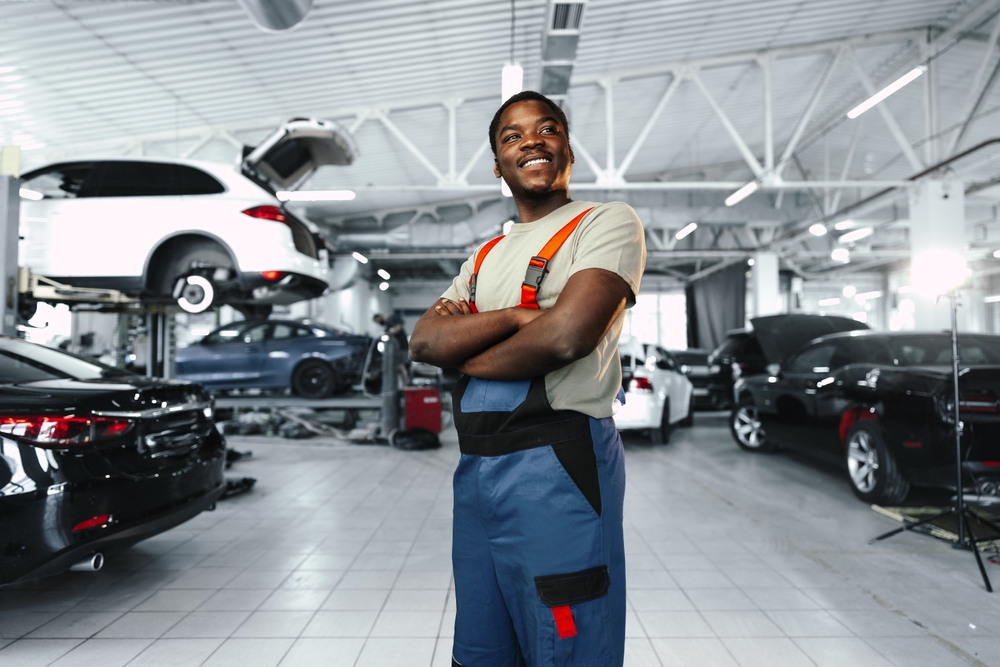 African man mechanic in uniform at the car repair station, portrait