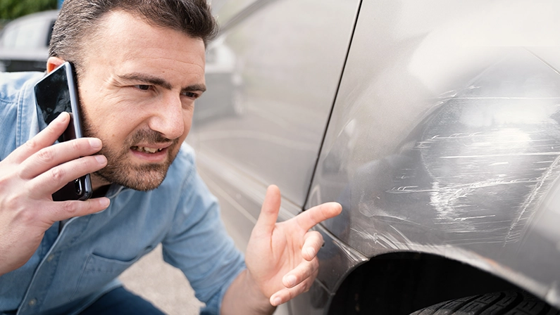 One man calling insurance reporting car body scratches