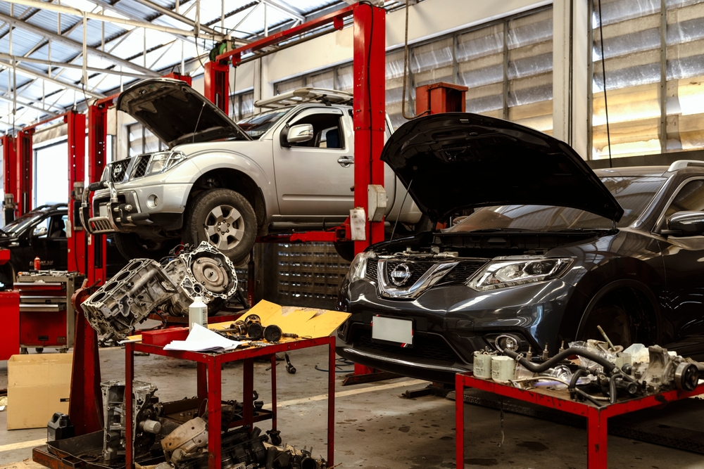 A busy car repair workshop with multiple cars on lifts and tools scattered around