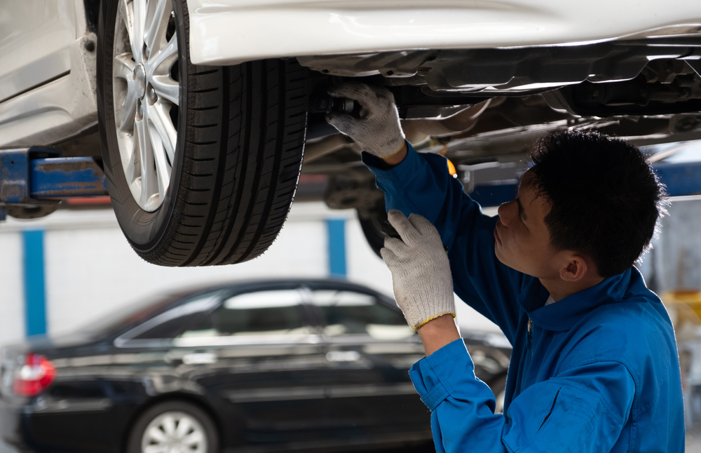 Mechanic fixing car suspension with car lifting. Mechanic checking tire with car lifting.