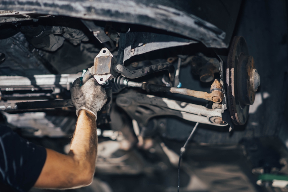 car suspension diagnostics, auto mechanic touches suspension arms and silent blocks