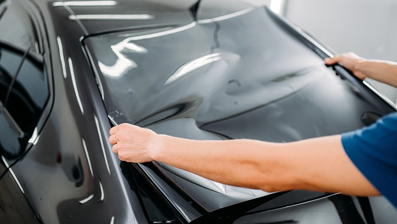 Male specialist with car tinting film in hands