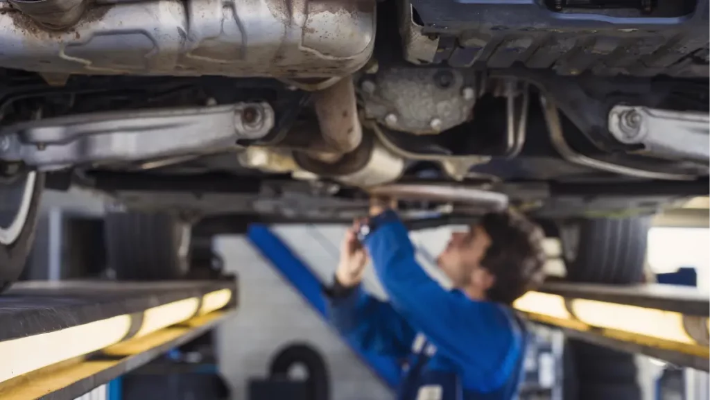 Exhaust of a car on the bridge at a auto repair shop with a mechanic underneath