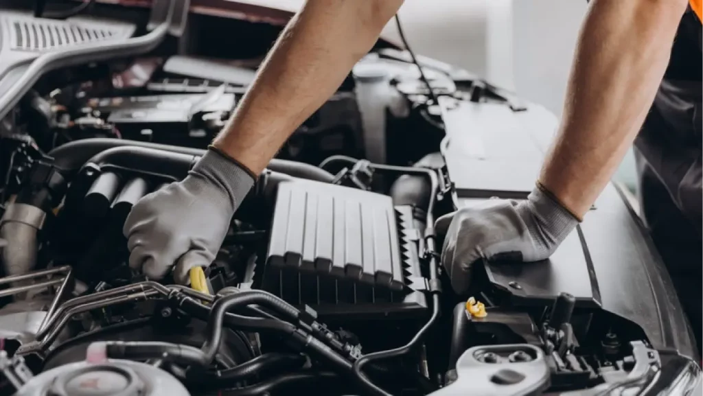 Close-up shot of unrecognisable man wearing gray glove inspecting car engine and interior of hood of car