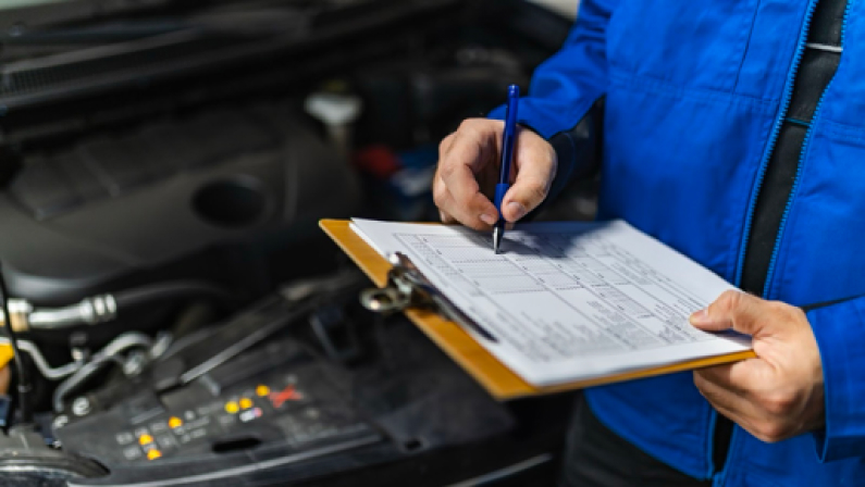A skilled mechanic reviews a detailed maintenance checklist while inspecting the engine of a car in a well-equipped workshop, ensuring proper functionality and safety.