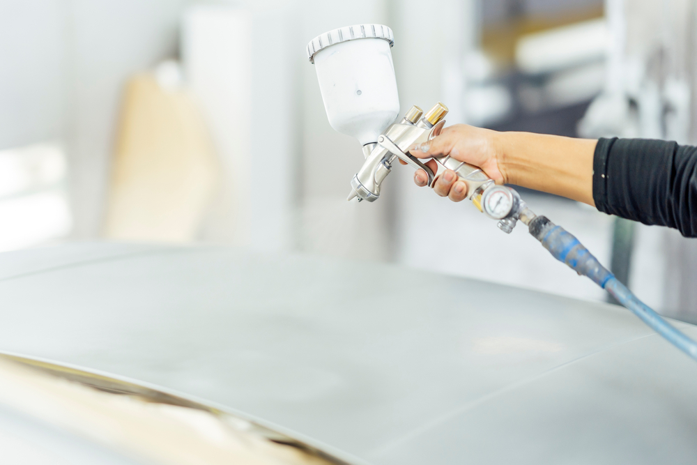 Close-up of a bodywork mechanic working in the workshop painting a car