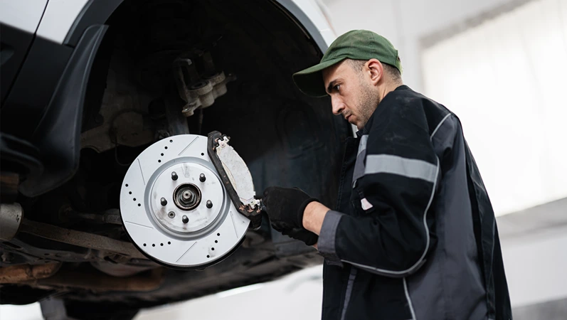A professional mechanic closely inspects a car's brake disc, demonstrating precision and expertise in an auto repair shop environment.